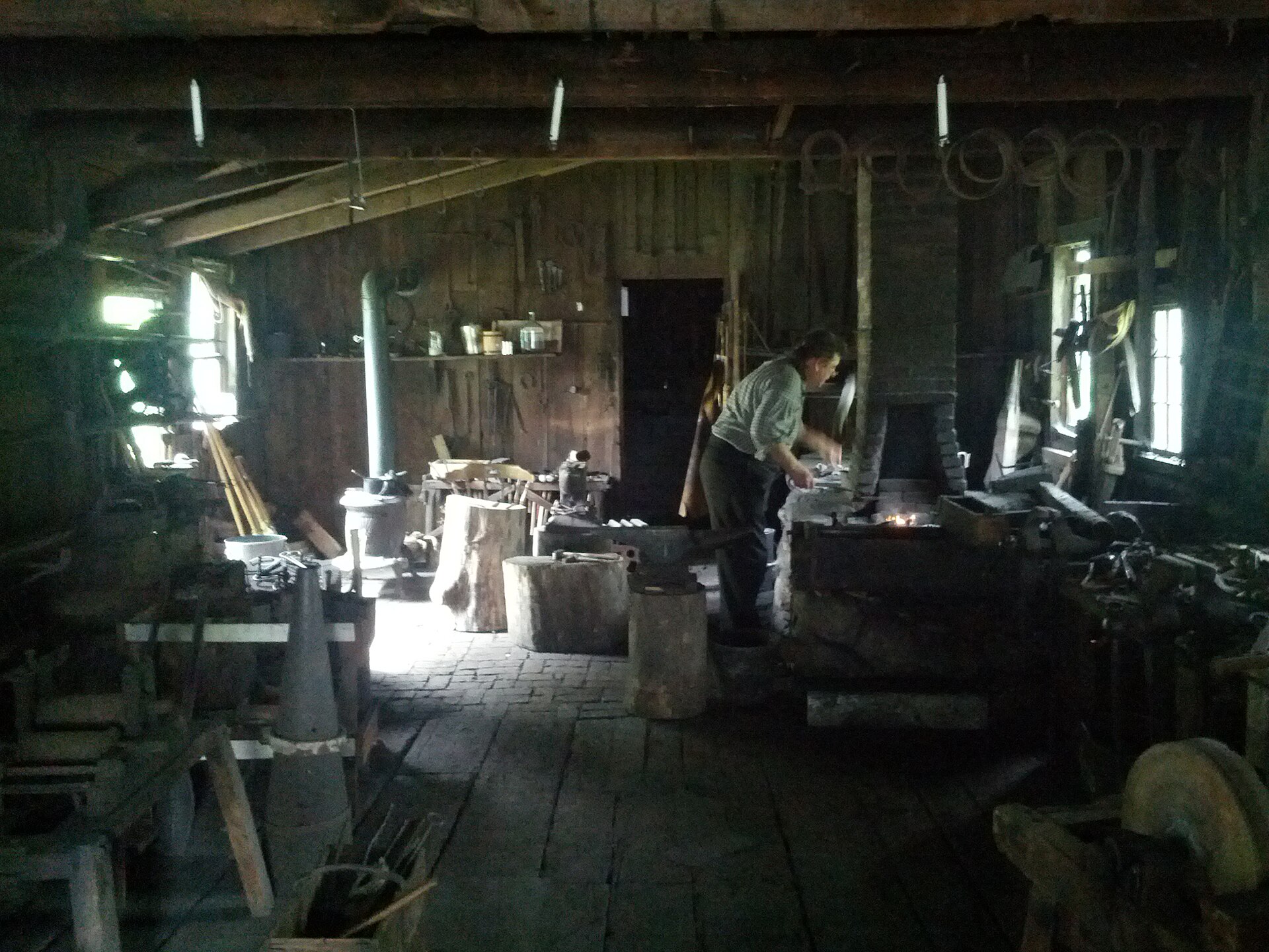 Forge traditionnelle : enclume, établi et artisan au foyer